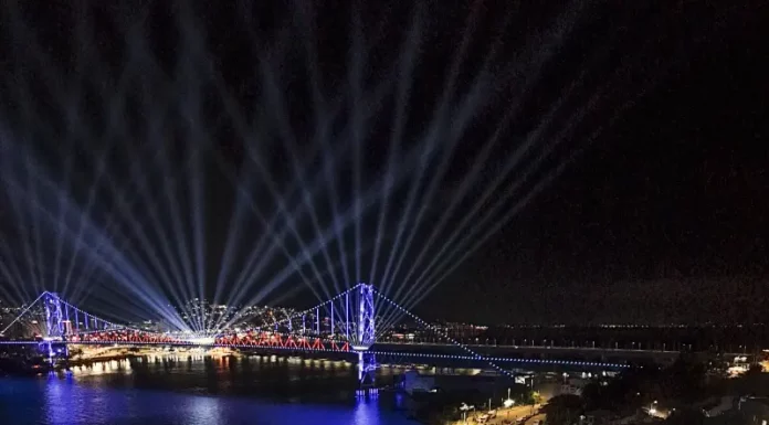 Centenário da Ponte Hercílio Luz reúne cerca de 100 mil pessoas no fim de semana Vista aérea mostra o público reunido na Beira-Mar Continental durante as comemorações do centenário da Ponte Hercílio Luz, em Florianópolis, com palco de shows, iluminação especial e feixes de luz sobre a ponte durante evento noturno.