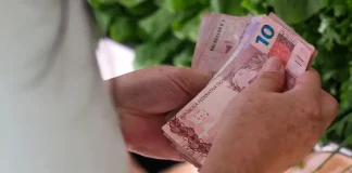 Pessoa segurando notas de dinheiro em real nas mãos, imagem usada para ilustrar dados sobre Bolsa Família e programas sociais no Brasil.