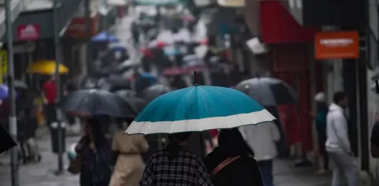 Chuva retorna a Santa Catarina no fim de semana e temperaturas seguem baixas Pessoas caminhando com guarda-chuvas no centro da cidade, mostrando que a chuva voltou no final de semana