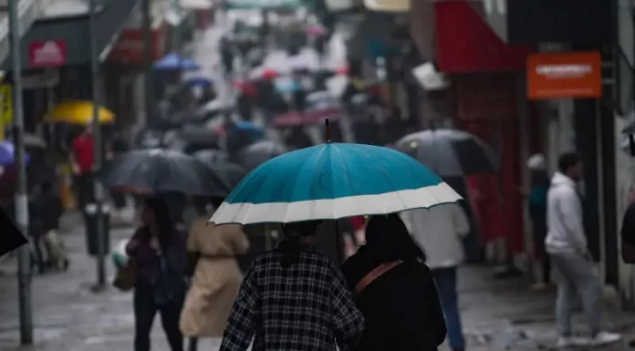 Chuva retorna a Santa Catarina no fim de semana e temperaturas seguem baixas Pessoas caminhando com guarda-chuvas no centro da cidade, mostrando que a chuva voltou no final de semana