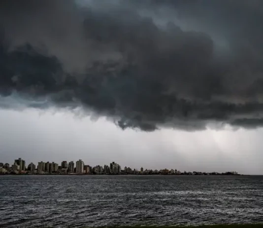 Nuvens escuras e densas avançam sobre o mar e a área urbana no litoral de Santa Catarina, indicando a chegada de temporais associados à formação de um ciclone extratropical. A imagem ilustra o cenário de instabilidade, com risco de chuva forte, ventos intensos e mar agitado previstos para o fim de semana no estado.