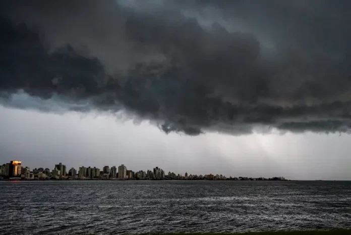 Nuvens escuras e densas avançam sobre o mar e a área urbana no litoral de Santa Catarina, indicando a chegada de temporais associados à formação de um ciclone extratropical. A imagem ilustra o cenário de instabilidade, com risco de chuva forte, ventos intensos e mar agitado previstos para o fim de semana no estado.