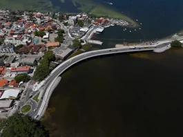 Imagem aérea da nova ponte da Lagoa da Conceição, em Florianópolis, mostrando a estrutura sobre a água, o tráfego de veículos e a ligação viária entre as margens, destacando sua função de melhorar a mobilidade e o acesso às praias do Leste.