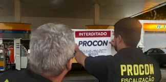 Agentes do Procon de Florianópolis colcando placa de interditado em posto de combustívies