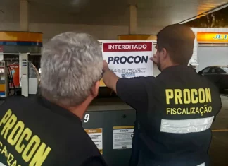 Agentes do Procon de Florianópolis colcando placa de interditado em posto de combustívies
