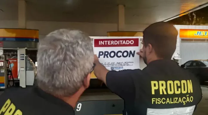 Agentes do Procon de Florianópolis colcando placa de interditado em posto de combustívies