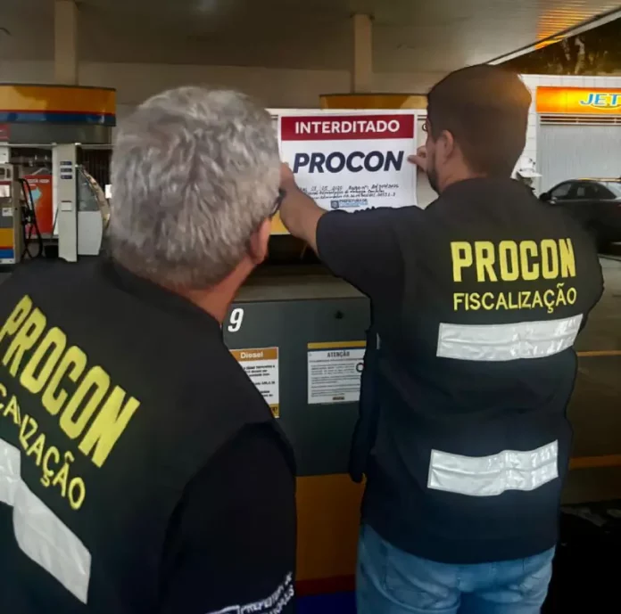 Agentes do Procon de Florianópolis colcando placa de interditado em posto de combustívies