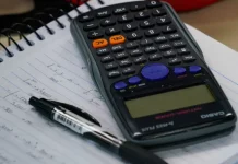 Mesa com calculadora, caderno e caneta, representando planejamento financeiro e organização de dívidas no contexto do programa Recupera Mais.