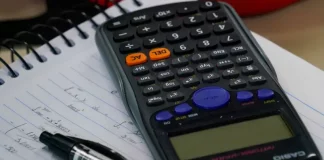 Mesa com calculadora, caderno e caneta, representando planejamento financeiro e organização de dívidas no contexto do programa Recupera Mais.