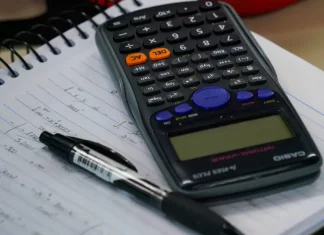 Mesa com calculadora, caderno e caneta, representando planejamento financeiro e organização de dívidas no contexto do programa Recupera Mais.
