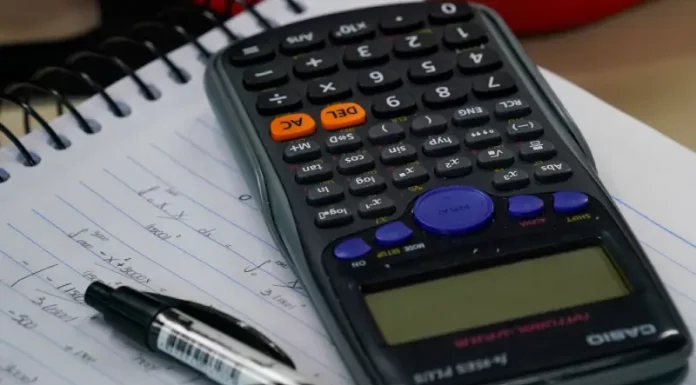 Mesa com calculadora, caderno e caneta, representando planejamento financeiro e organização de dívidas no contexto do programa Recupera Mais.