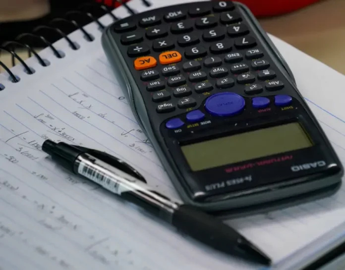 Mesa com calculadora, caderno e caneta, representando planejamento financeiro e organização de dívidas no contexto do programa Recupera Mais.