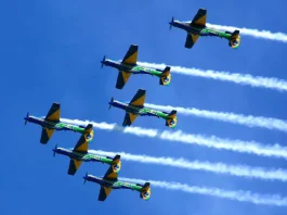 Esquadrilha da Fumaça se apresenta em Florianópolis neste domingo Seis aeronaves da Esquadrilha da Fumaça realizam voo em formação no céu azul, deixando rastros de fumaça branca. A imagem ilustra a apresentação aérea anunciada para Florianópolis e destaca o caráter de espetáculo visual e demonstração de precisão da Força Aérea Brasileira para o público.