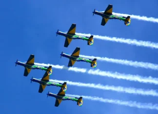 Esquadrilha da Fumaça se apresenta em Florianópolis neste domingo Seis aeronaves da Esquadrilha da Fumaça realizam voo em formação no céu azul, deixando rastros de fumaça branca. A imagem ilustra a apresentação aérea anunciada para Florianópolis e destaca o caráter de espetáculo visual e demonstração de precisão da Força Aérea Brasileira para o público.