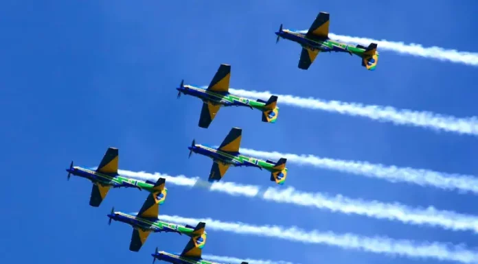 Esquadrilha da Fumaça se apresenta em Florianópolis neste domingo Seis aeronaves da Esquadrilha da Fumaça realizam voo em formação no céu azul, deixando rastros de fumaça branca. A imagem ilustra a apresentação aérea anunciada para Florianópolis e destaca o caráter de espetáculo visual e demonstração de precisão da Força Aérea Brasileira para o público.