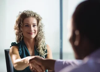 Feirão de Empregos oferece mais de 400 vagas em Biguaçu Mulher participa de uma entrevista de emprego e aperta a mão de um recrutador, representando oportunidades de contratação durante o Feirão de Empregos de Biguaçu