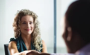 Feirão de Empregos oferece mais de 400 vagas em Biguaçu Mulher participa de uma entrevista de emprego e aperta a mão de um recrutador, representando oportunidades de contratação durante o Feirão de Empregos de Biguaçu