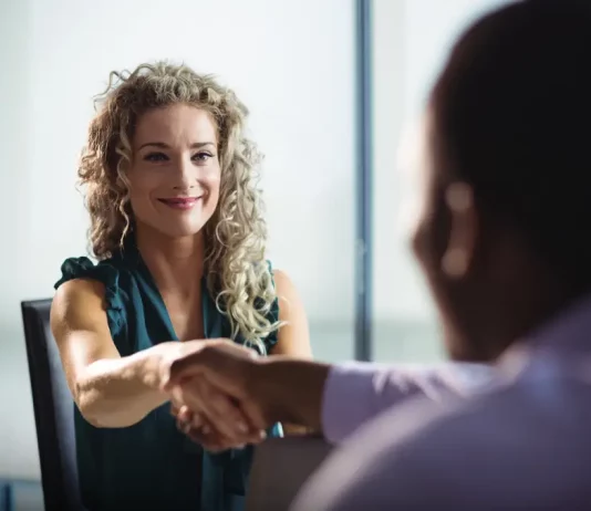 Feirão de Empregos oferece mais de 400 vagas em Biguaçu Mulher participa de uma entrevista de emprego e aperta a mão de um recrutador, representando oportunidades de contratação durante o Feirão de Empregos de Biguaçu