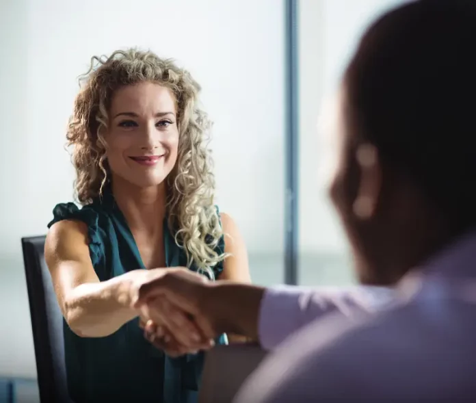 Mulher participa de uma entrevista de emprego e aperta a mão de um recrutador, representando oportunidades de contratação durante o Feirão de Empregos de Biguaçu
