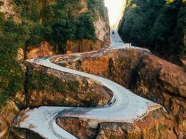 Vista aérea da Serra do Corvo Branco, em Santa Catarina, mostrando o trecho da SC-370 em obras de pavimentação em concreto. A imagem destaca as curvas da rodovia entre paredões rochosos, evidenciando os investimentos em infraestrutura, segurança viária e melhoria da ligação entre a Serra e o Litoral catarinense.