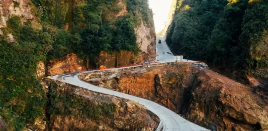 Vista aérea da Serra do Corvo Branco, em Santa Catarina, mostrando o trecho da SC-370 em obras de pavimentação em concreto. A imagem destaca as curvas da rodovia entre paredões rochosos, evidenciando os investimentos em infraestrutura, segurança viária e melhoria da ligação entre a Serra e o Litoral catarinense.