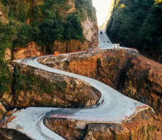Vista aérea da Serra do Corvo Branco, em Santa Catarina, mostrando o trecho da SC-370 em obras de pavimentação em concreto. A imagem destaca as curvas da rodovia entre paredões rochosos, evidenciando os investimentos em infraestrutura, segurança viária e melhoria da ligação entre a Serra e o Litoral catarinense.
