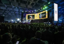 Auditório lotado durante uma edição do Summit Cidades, com público sentado diante de um grande palco iluminado e telões exibindo apresentações. A imagem ilustra a dimensão do evento, que reúne milhares de participantes para debater gestão pública, desenvolvimento urbano, inovação, mobilidade e políticas para o futuro das cidades em Florianópolis.