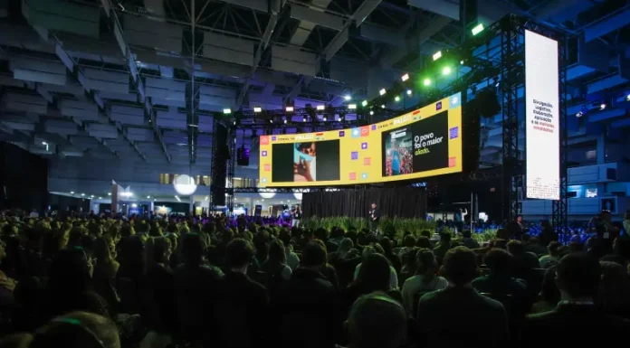 Auditório lotado durante uma edição do Summit Cidades, com público sentado diante de um grande palco iluminado e telões exibindo apresentações. A imagem ilustra a dimensão do evento, que reúne milhares de participantes para debater gestão pública, desenvolvimento urbano, inovação, mobilidade e políticas para o futuro das cidades em Florianópolis.
