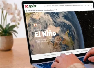Pessoa utiliza um notebook exibindo a página especial “Fenômeno Climático El Niño” no portal da Secretaria de Estado da Proteção e Defesa Civil de Santa Catarina (SDC/SC). A imagem ilustra o acesso à plataforma criada para divulgar informações atualizadas, orientações de prevenção, documentos oficiais e conteúdos educativos sobre os impactos do El Niño e as ações de preparação da Defesa Civil no estado.