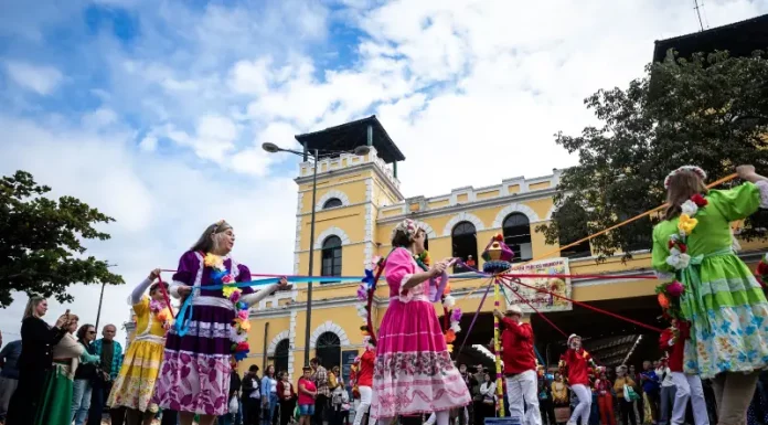 Dia do Manezinho celebra cultura e tradições de Florianópolis Participantes vestidos com trajes coloridos realizam uma apresentação cultural em frente ao Mercado Público de Florianópolis durante uma celebração do Dia do Manezinho. A imagem ilustra a valorização das tradições, da cultura popular e das manifestações folclóricas que fazem parte da identidade da cidade.