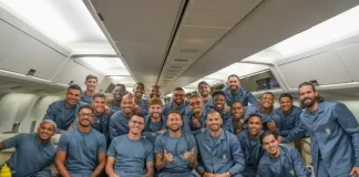 Jogadores e integrantes da comissão técnica da Seleção Brasileira posam para uma foto dentro da aeronave que transporta a delegação aos Estados Unidos para a disputa da Copa do Mundo de 2026. A imagem registra o embarque da equipe e o início da viagem para o torneio.
