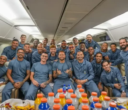 Jogadores e integrantes da comissão técnica da Seleção Brasileira posam para uma foto dentro da aeronave que transporta a delegação aos Estados Unidos para a disputa da Copa do Mundo de 2026. A imagem registra o embarque da equipe e o início da viagem para o torneio.
