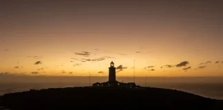 Foto de um farol no por de sol, mostrando temperatura tipica de outono no início de junho