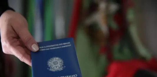 Sine oferece mais de 8 mil vagas de emprego em Santa Catarina Mão segurando carteira de trabalho, simbolizando as vagas de emprego em Santa Catarina