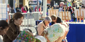 Participantes confeccionam renda de bilro durante atividade cultural ao ar livre no Largo da Alfândega, em celebração aos 39 anos da Fundação Franklin Cascaes, em Florianópolis.