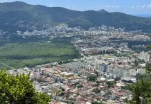 Vista panorâmica de Florianópolis mostra áreas urbanizadas, vegetação preservada e bairros da Capital, ilustrando o crescimento urbano e o planejamento territorial previsto no Plano Diretor.