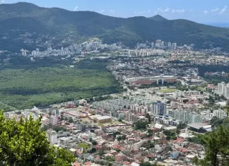 Vista panorâmica de Florianópolis mostra áreas urbanizadas, vegetação preservada e bairros da Capital, ilustrando o crescimento urbano e o planejamento territorial previsto no Plano Diretor.