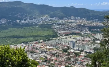 Vista panorâmica de Florianópolis mostra áreas urbanizadas, vegetação preservada e bairros da Capital, ilustrando o crescimento urbano e o planejamento territorial previsto no Plano Diretor.