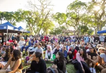 Foto mostra pessoas sentadas em área do Jardim Botânico prestigiando o Festival Tanabata Matsuri
