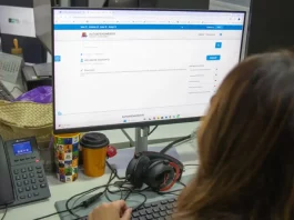 Servidora da prefeitura de São José olhando a tela de computador para solicitação de isenção do IPTU