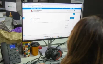 Servidora da prefeitura de São José olhando a tela de computador para solicitação de isenção do IPTU