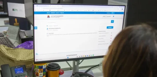 Servidora da prefeitura de São José olhando a tela de computador para solicitação de isenção do IPTU