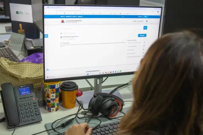 Servidora da prefeitura de São José olhando a tela de computador para solicitação de isenção do IPTU