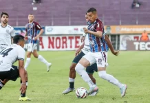 Jogadores de Caxias e Figueirense disputam partida de futebol no Estádio Centenário.