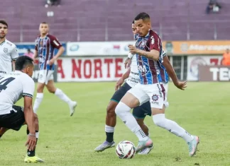 Jogadores de Caxias e Figueirense disputam partida de futebol no Estádio Centenário.