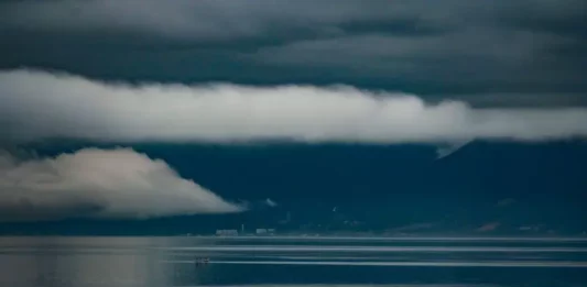 Foto do mar sob céu carregado de nuvens escuras e tempestade, com montanhas ao fundo, ilustrando a previsão do Fórum Climático de chuva acima da média e maior frequência de tempestades severas em Santa Catarina.