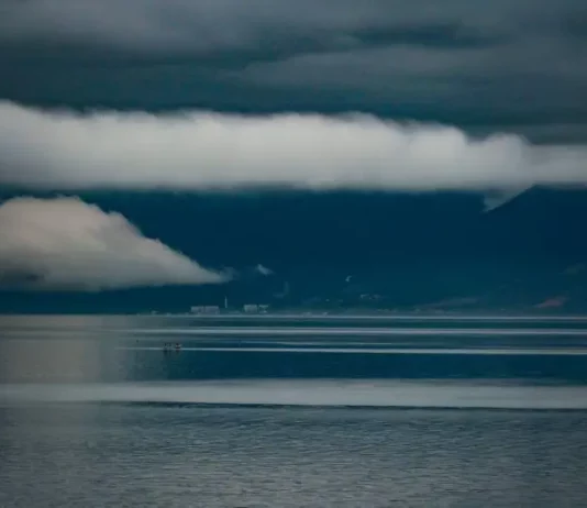 Foto do mar sob céu carregado de nuvens escuras e tempestade, com montanhas ao fundo, ilustrando a previsão do Fórum Climático de chuva acima da média e maior frequência de tempestades severas em Santa Catarina.