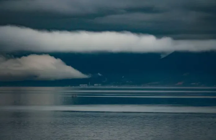 influência El Niño segundo Fórum Climático (1) Foto do mar sob céu carregado de nuvens escuras e tempestade, com montanhas ao fundo, ilustrando a previsão do Fórum Climático de chuva acima da média e maior frequência de tempestades severas em Santa Catarina.