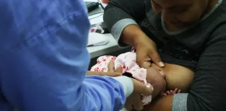 Foto de mãe amamentando criança com auxilio de enfermeira, simbolizando o curso de amamentação dutrante agosto dourado