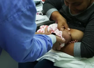 Foto de mãe amamentando criança com auxilio de enfermeira, simbolizando o curso de amamentação dutrante agosto dourado